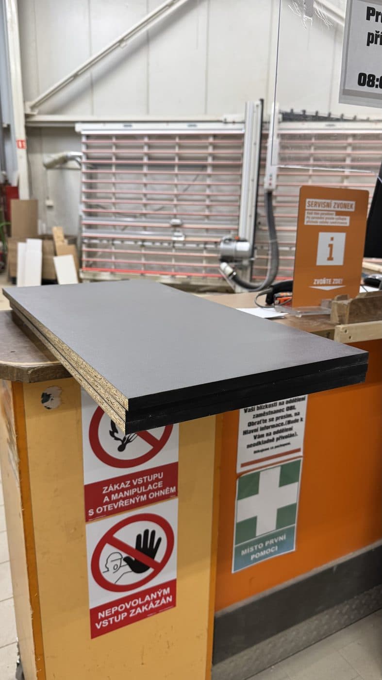 A freshly cut black panel resting on the counter of a cutting service.